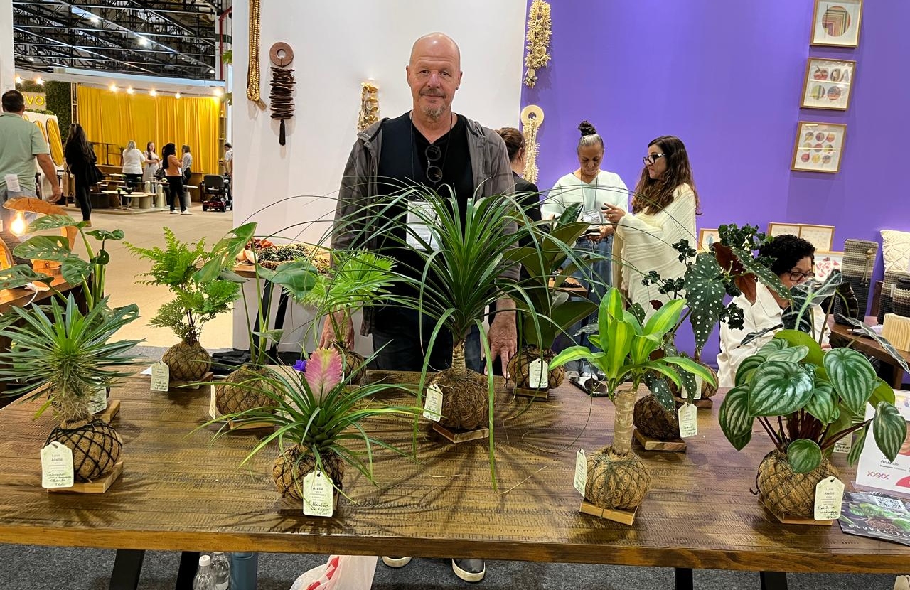 Homem branco no centro de uma mesa que contém várias plantas