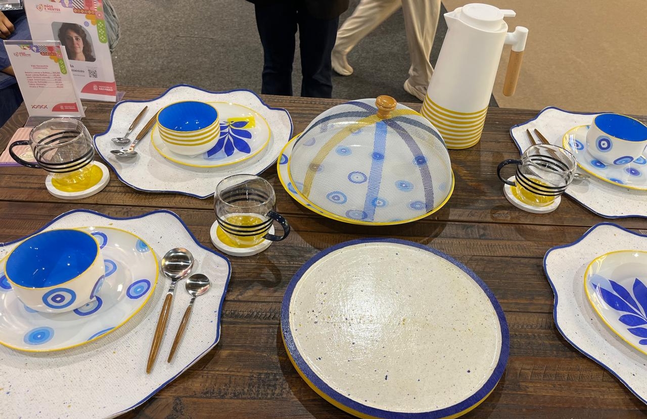 Mesa posta com jarra de suco, pratos e copos de vidro