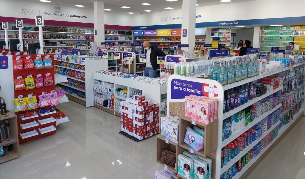 Pessoas transitam entre as gôndolas de uma unidade da farmais